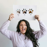 Caucasian woman with dark hair holding Pet Paw Collage above head