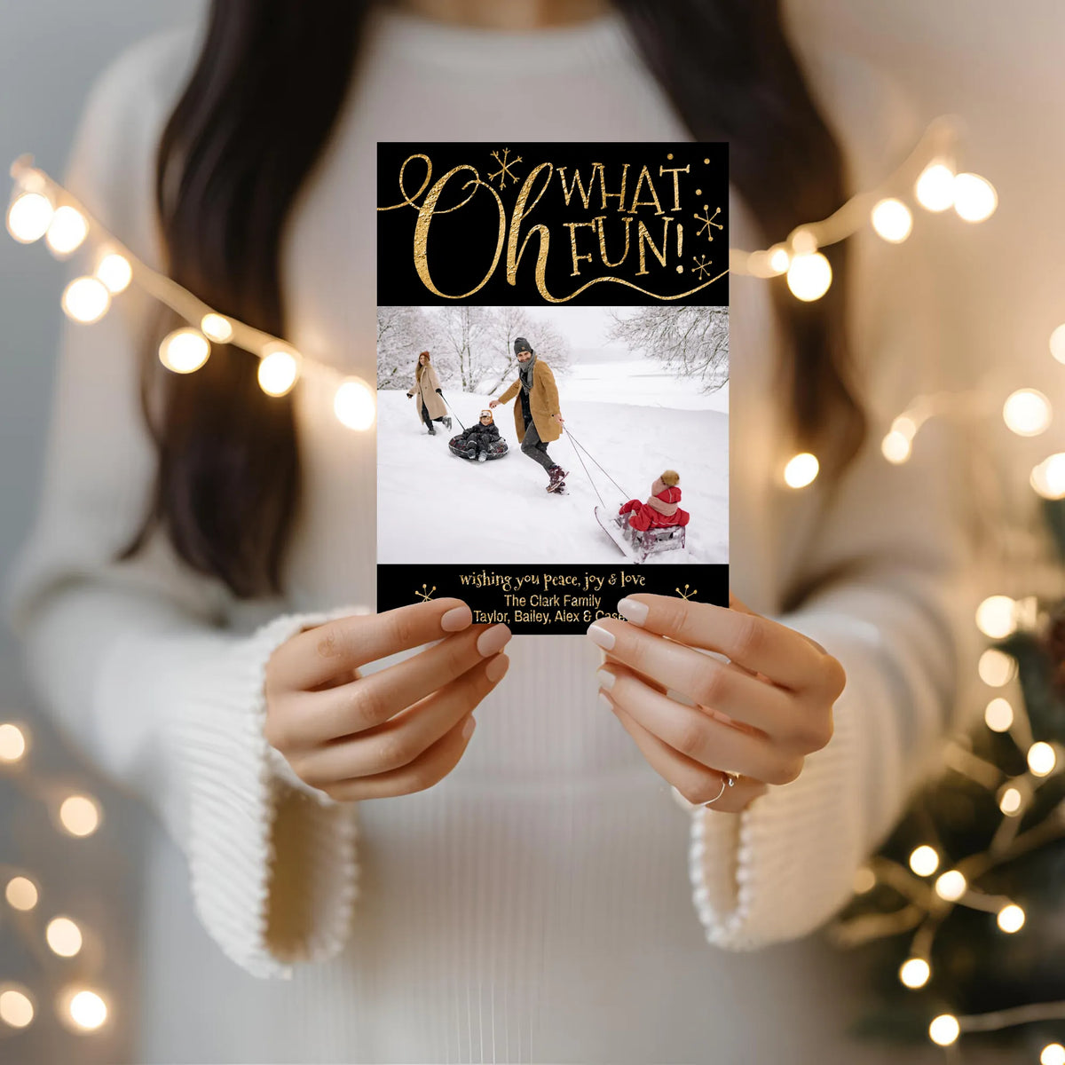 woman holding oh what fun photo card with string lights