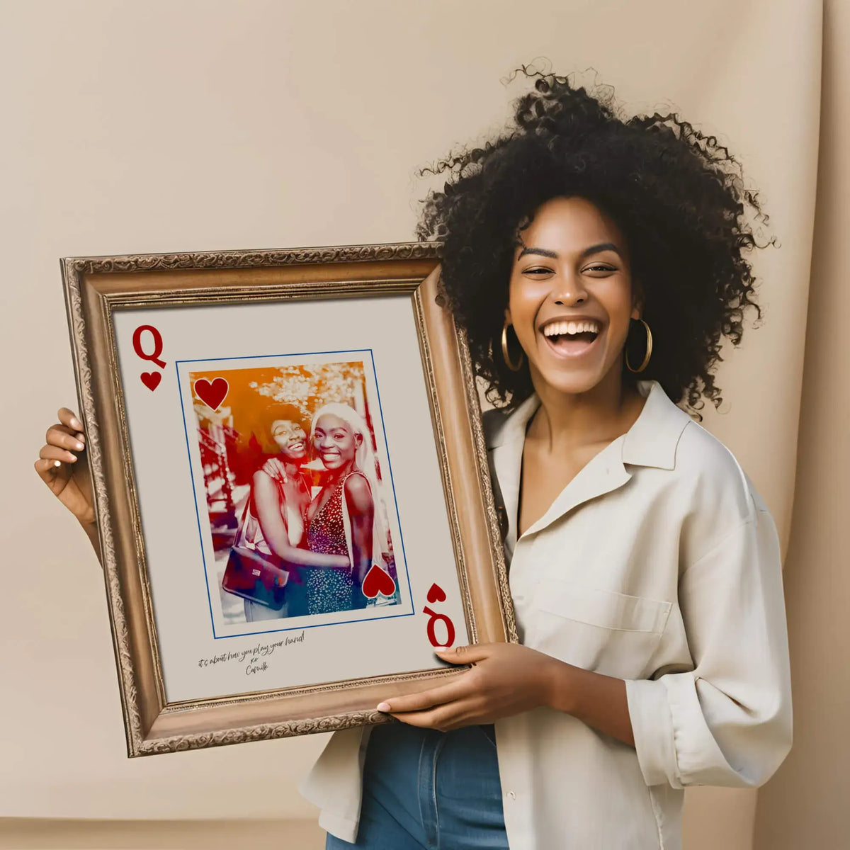 African American woman holding Queen of hearts portrait in golden frame